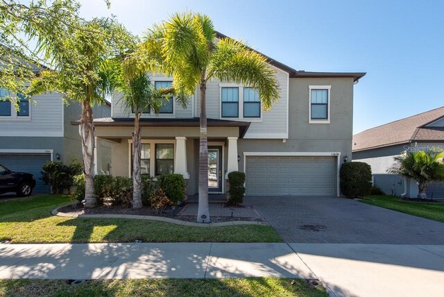 view of front of house with covered porch, an attached garage, stucco siding, and decorative driveway