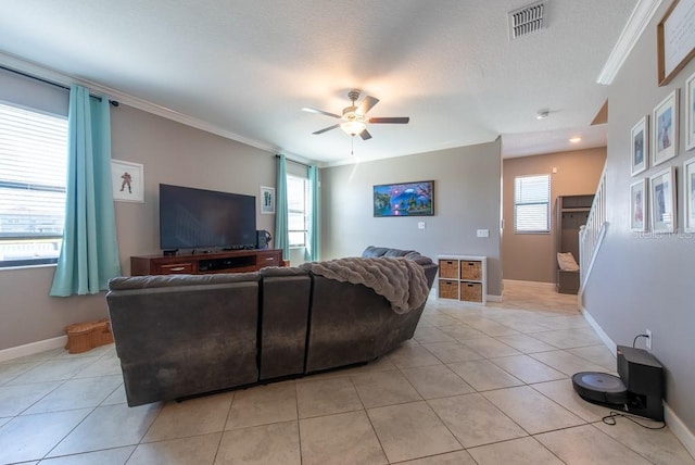 living area with light tile patterned floors, a ceiling fan, visible vents, and ornamental molding
