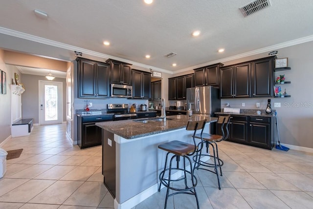 kitchen featuring a kitchen breakfast bar, a sink, light tile patterned flooring, stainless steel appliances, and visible vents