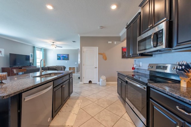 kitchen featuring dark stone countertops, a sink, crown molding, appliances with stainless steel finishes, and open floor plan