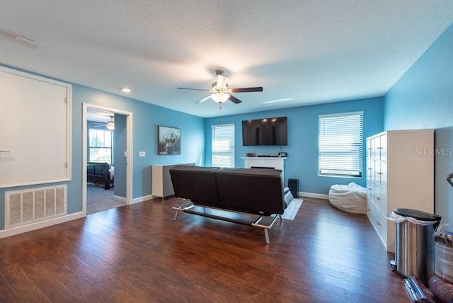 living area featuring wood finished floors, visible vents, baseboards, and ceiling fan