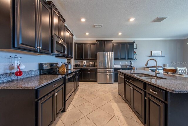 13639 Ashlar Slate Pl, Riverview, FL 33579 - kitchen featuring stainless steel appliances, a sink, ornamental molding, an island with sink, and dark stone countertops