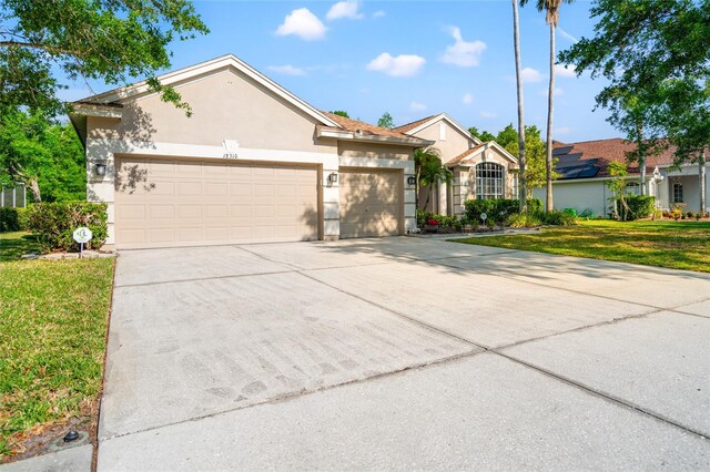 ranch-style house with stucco siding, an attached garage, driveway, and a front lawn