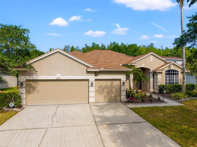 view of front of house featuring a garage, concrete driveway, a front lawn, and stucco siding