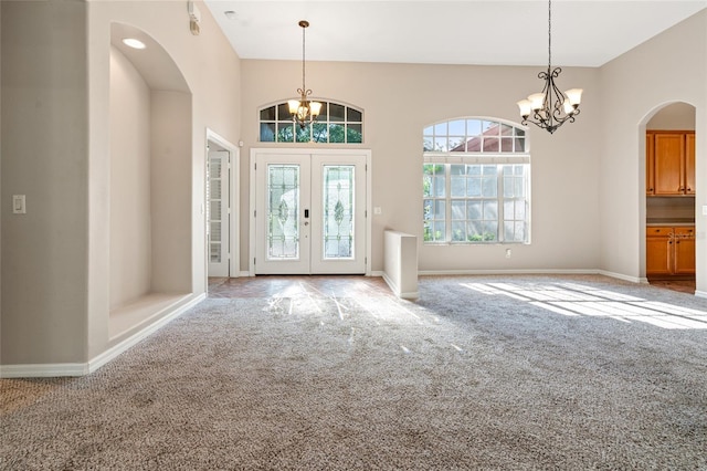 foyer featuring baseboards, carpet, and a chandelier