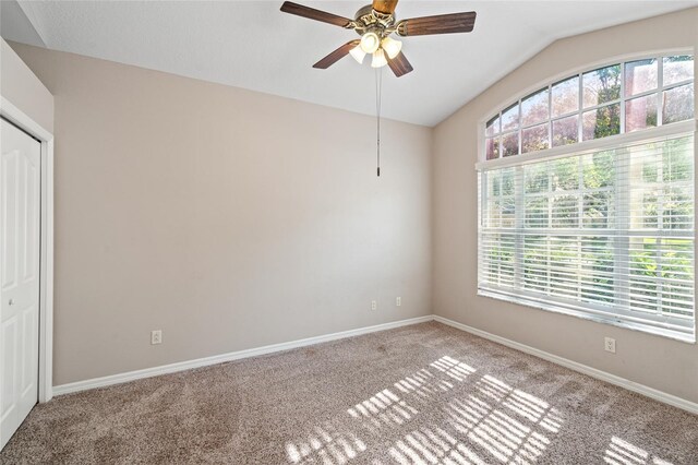 unfurnished bedroom with baseboards, lofted ceiling, a closet, ceiling fan, and carpet floors