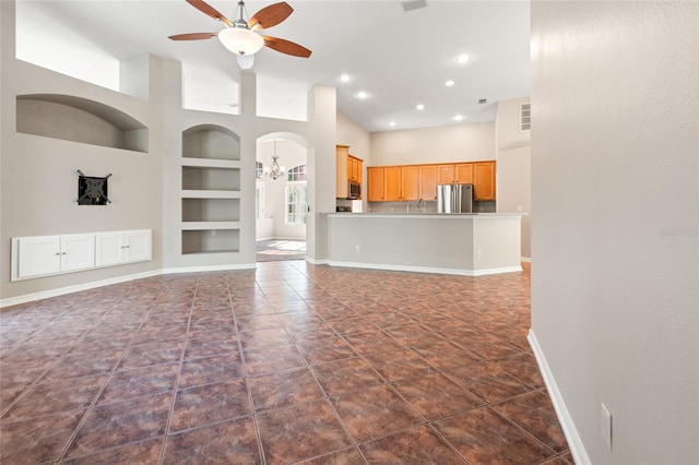 unfurnished living room featuring high vaulted ceiling, ceiling fan with notable chandelier, built in features, baseboards, and visible vents