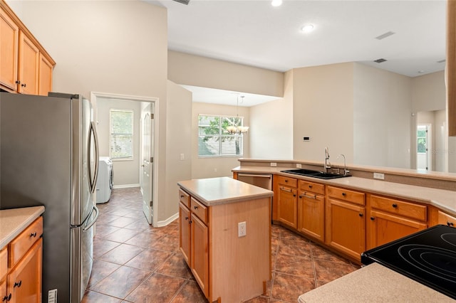 kitchen with stainless steel appliances, light countertops, a sink, independent washer and dryer, and a notable chandelier