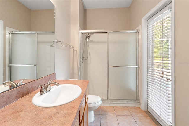 bathroom with toilet, vanity, tile patterned floors, and a stall shower