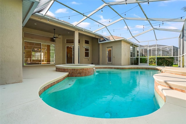 view of pool with glass enclosure, a ceiling fan, a pool with connected hot tub, and a patio