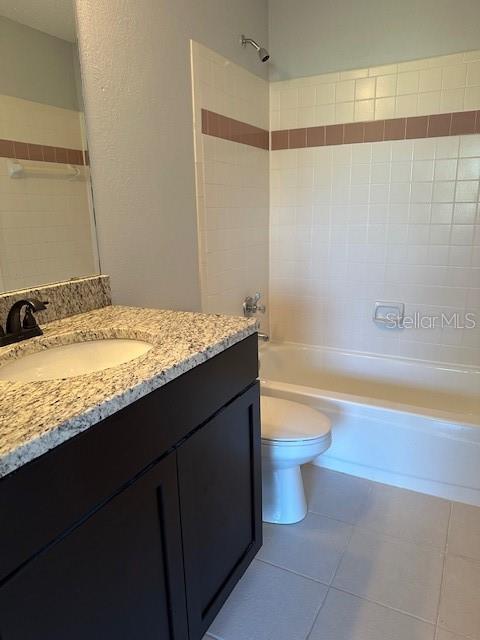 bathroom featuring vanity, toilet, tile patterned flooring, and tub / shower combination