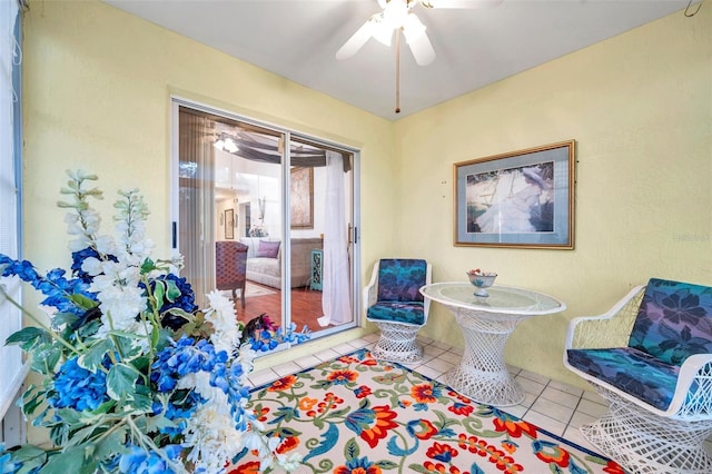 living area with a ceiling fan and tile patterned flooring