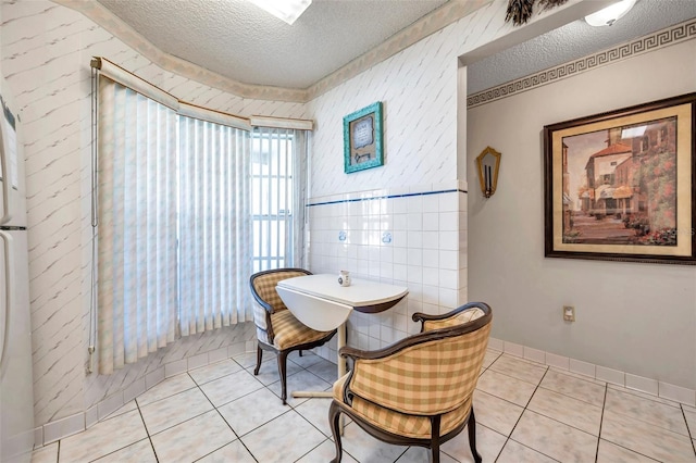 dining area with a textured ceiling, light tile patterned flooring, and baseboards