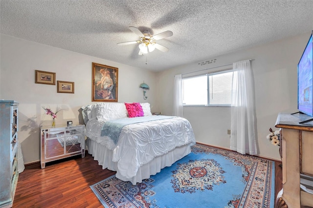 bedroom featuring a textured ceiling, wood finished floors, baseboards, and a ceiling fan