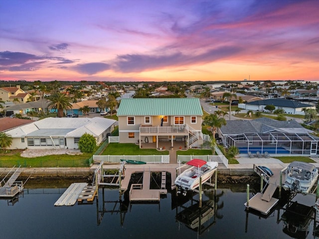 view of dock with boat lift, a water view, a residential view, and a fenced backyard