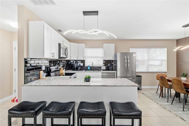 5519 Homewood Dr, Sarasota, FL 34232 - kitchen with light tile patterned floors, a peninsula, visible vents, a sink, and stainless steel appliances