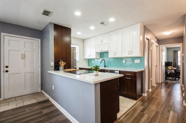 1821 Bough Ave Unit 4, Clearwater, FL 33760 - kitchen featuring light countertops, white cabinetry, light wood-style flooring, decorative backsplash, and dark brown cabinets