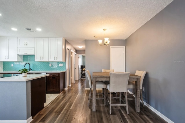 1821 Bough Ave Unit 4, Clearwater, FL 33760 - kitchen featuring light countertops, wood finished floors, a chandelier, decorative backsplash, and white cabinetry