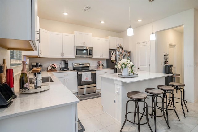 kitchen featuring visible vents, white cabinetry, appliances with stainless steel finishes, a breakfast bar, and light tile patterned floors