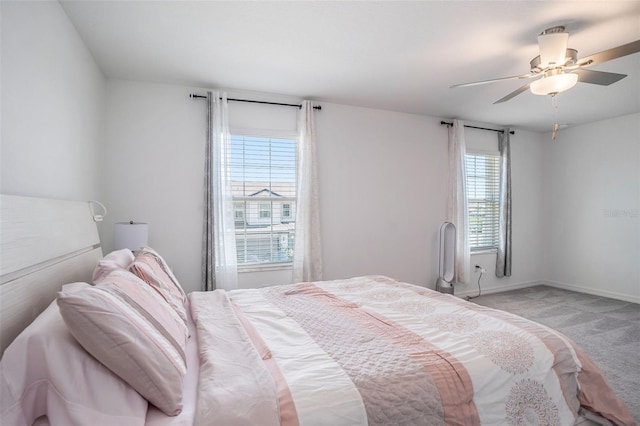 bedroom featuring light colored carpet, baseboards, and a ceiling fan
