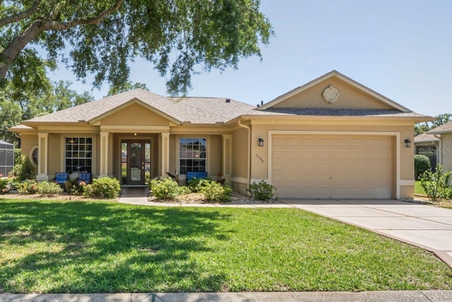 ranch-style home featuring a garage, driveway, a shingled roof, a front yard, and stucco siding