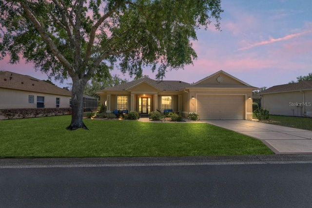 ranch-style home with french doors, driveway, an attached garage, a yard, and stucco siding