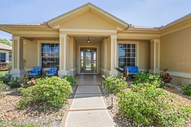 entrance to property featuring covered porch and stucco siding