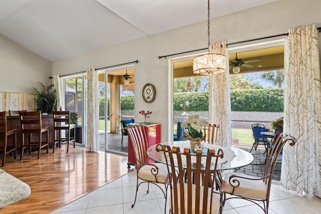dining space featuring ceiling fan with notable chandelier and vaulted ceiling