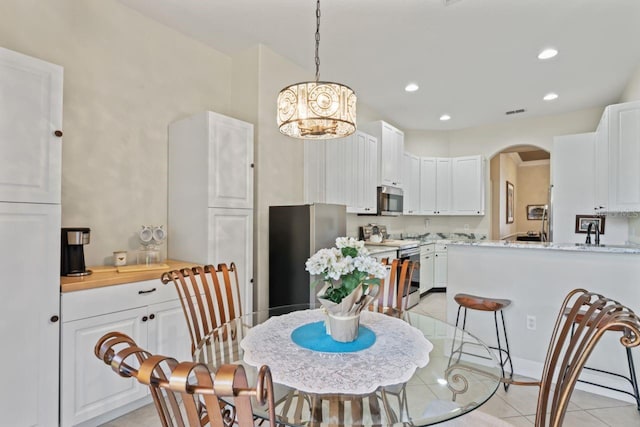 dining area with recessed lighting, arched walkways, light tile patterned flooring, and an inviting chandelier