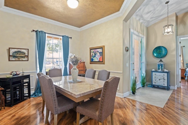 dining space with an inviting chandelier, crown molding, light wood-style floors, and a textured ceiling