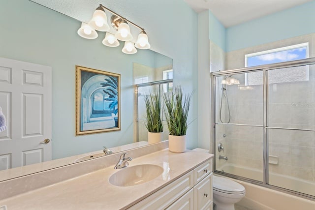 bathroom with vanity, toilet, and bath / shower combo with glass door