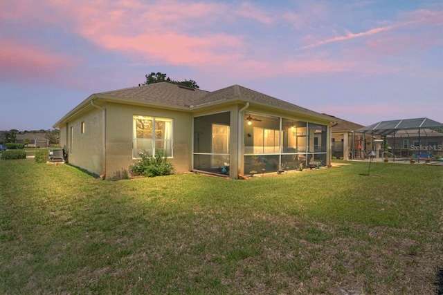 back of property at dusk featuring a lawn and central AC