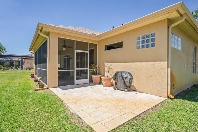rear view of house with a lawn, a sunroom, a patio area, and stucco siding
