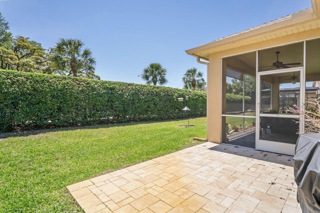 view of yard with ceiling fan, a sunroom, and a patio