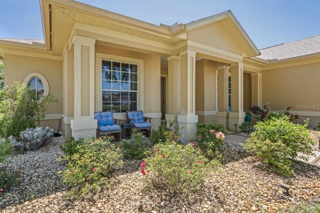 property entrance with roof with shingles and stucco siding