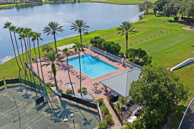 community pool featuring a yard, view of golf course, a water view, and fence