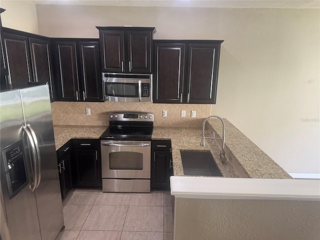 778 Spring Flowers Trl, Brandon, FL 33511 - kitchen featuring light stone counters, decorative backsplash, stainless steel appliances, a sink, and light tile patterned flooring