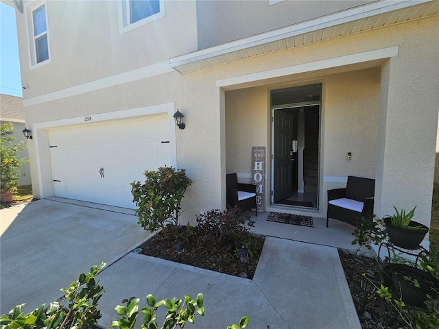 entrance to property featuring an attached garage, driveway, and stucco siding