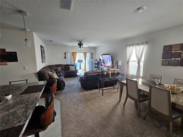 carpeted dining space with a ceiling fan, visible vents, and a textured ceiling