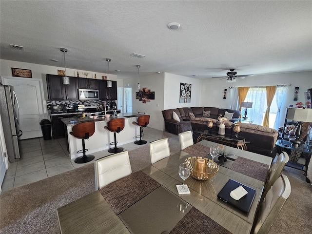 dining room featuring visible vents, a ceiling fan, light carpet, light tile patterned floors, and a textured ceiling