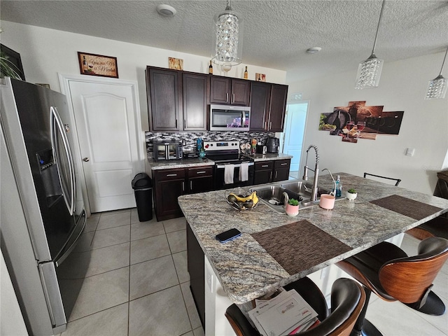 kitchen with stainless steel appliances, a breakfast bar, a sink, pendant lighting, and decorative backsplash