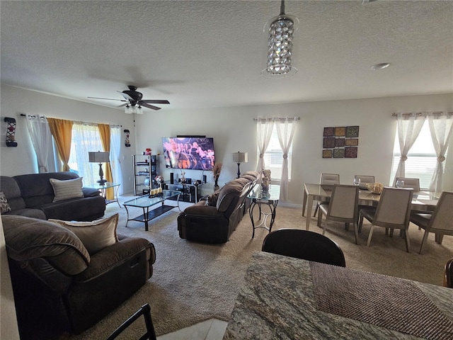 living room with a textured ceiling, ceiling fan, a wealth of natural light, and light carpet
