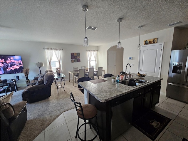 kitchen featuring stainless steel appliances, visible vents, a sink, arched walkways, and open floor plan