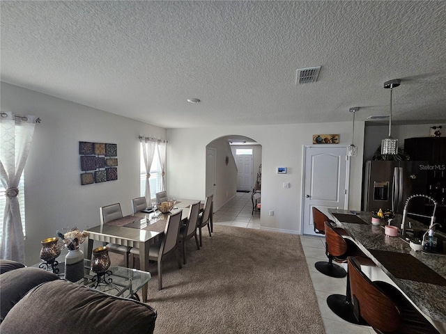 dining room with arched walkways, a textured ceiling, visible vents, and light tile patterned floors