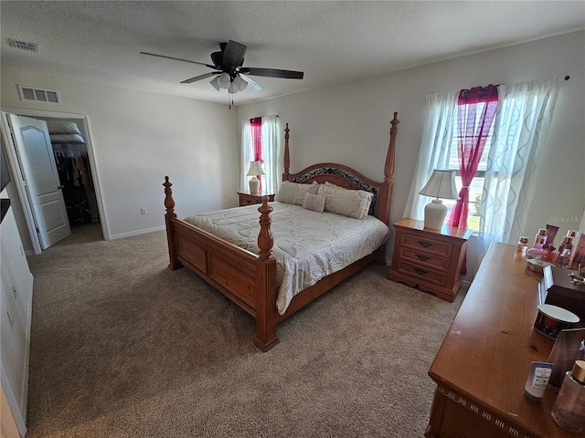 bedroom featuring a spacious closet, light carpet, a ceiling fan, and visible vents