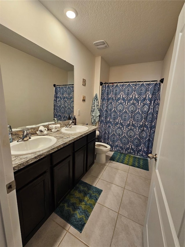 bathroom with visible vents, a sink, a textured ceiling, and double vanity