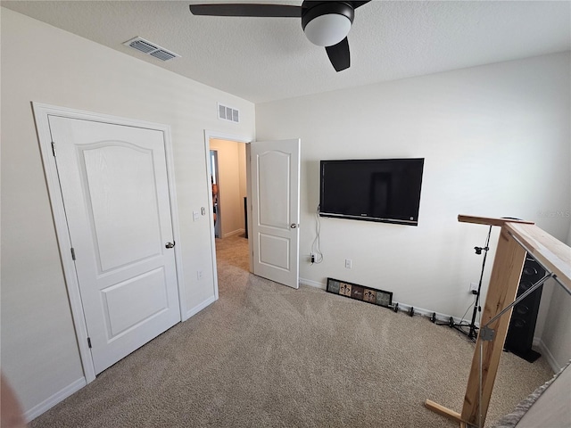interior space with carpet, visible vents, baseboards, and ceiling fan