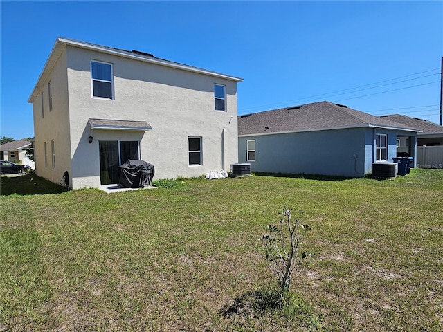 back of house with a yard, central AC, and stucco siding