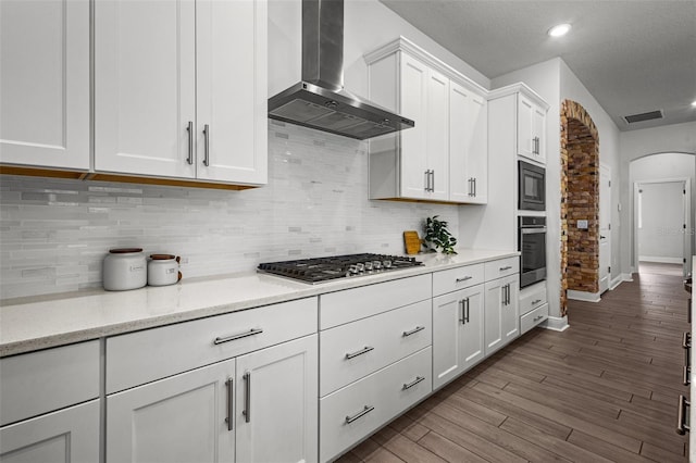 15329 Renaissance Ave, Odessa, FL 33556 - kitchen featuring white cabinets, stainless steel appliances, wall chimney range hood, visible vents, and arched walkways