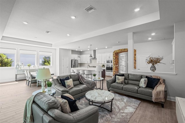 15329 Renaissance Ave, Odessa, FL 33556 - living area with a raised ceiling, light wood-type flooring, visible vents, and baseboards